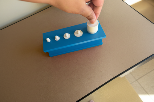 Child playing with blue Montessori cylinder toy